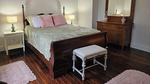 A neatly arranged bedroom with a wooden bed, two bedside tables with lamps, a dresser, and a mirror.
