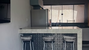Una cocina moderna con una isla central, taburetes de bar y un amplio ventanal.