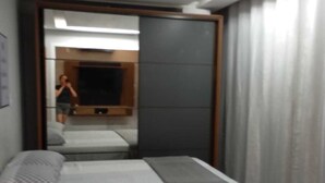 Un dormitorio moderno con cama, espejo y televisión.