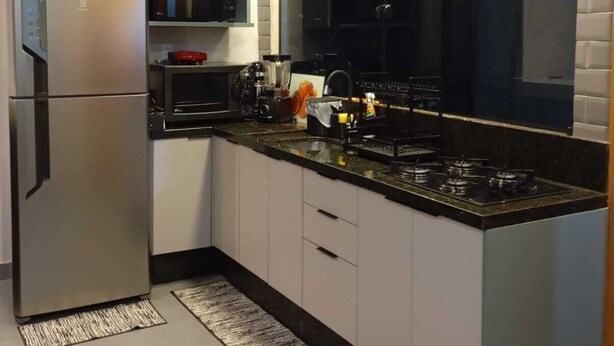 Una cocina moderna con un refrigerador de acero inoxidable, un microondas, una estufa y un ventanal amplio.
