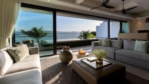 Ein modernes Wohnzimmer mit großem Fenster, einer Couch, einem Couchtisch und Deckenventilatoren.