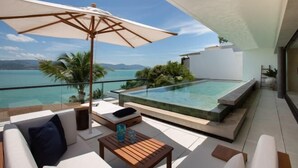 Ein moderner Außenbereich zum Entspannen mit Pool, Sitzgelegenheiten und Meerblick.