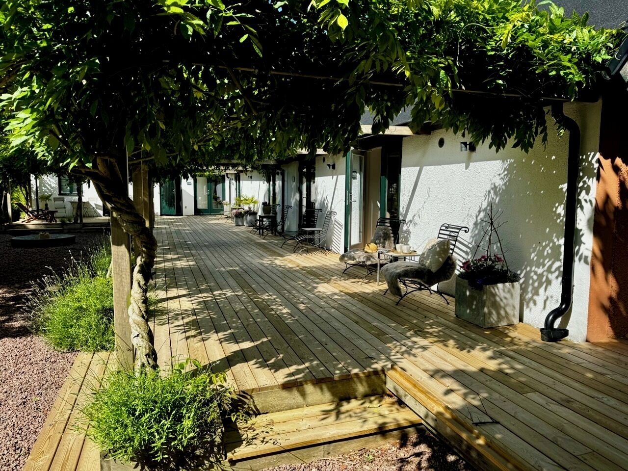 Un espacio al aire libre cubierto con suelo de madera, asientos y plantas en macetas.