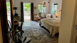 Ein Schlafzimmer mit einem Bett, einem Sessel, einem Schreibtisch, einer Lampe und einem Fenster.