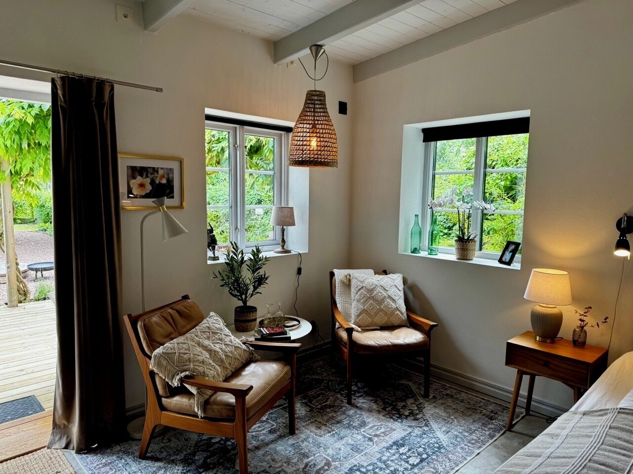 Un cuarto acogedor con dos sillones de cuero, una mesita, una lámpara y un ventanal con vistas a zonas verdes.