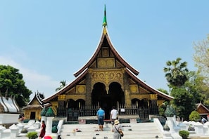 A temple with a pointed roof and ornate decorations. - We House Guest Hotel (Luang Prabang)