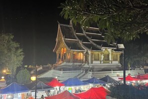 A traditional building with a tiered roof, surrounded by red and blue tents, likely indicating a market or event. - We House Guest Hotel (Luang Prabang)
