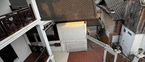 Un immeuble résidentiel à plusieurs niveaux, doté d’un espace extérieur couvert, d’un escalier et d’une cour clôturée.