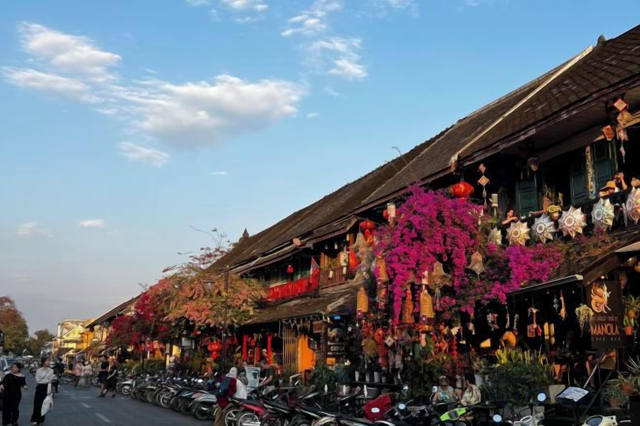A street lined with traditional buildings, some with balconies adorned with flowers.