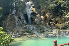 A natural water cascade surrounded by rocky terrain and greenery. - We House Guest Hotel (Luang Prabang)