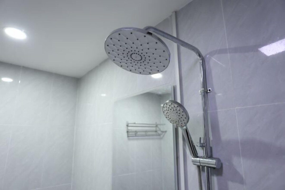 Une douche moderne équipée d’un pommeau de douche à main et d’un pommeau de douche fixe fixé au mur.