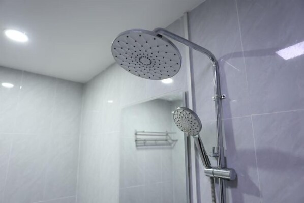 Une douche moderne équipée d’un pommeau de douche à main et d’un pommeau de douche fixe fixé au mur.