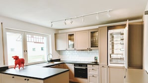 A modern kitchen with light wood cabinets, a central island, and a built-in oven. - NEW: Spacious suite with private terrace | 10 min from Rothenburg, ob der Tauber (Schrozberg)