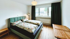 A room with a bed, a small table, a floor lamp, and a window with curtains. - NEW: Spacious suite with private terrace | 10 min from Rothenburg, ob der Tauber (Schrozberg)