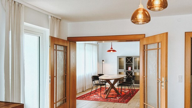 A spacious room with wooden flooring, a dining area with a red rug, and a kitchen in the background. - NEW: Spacious suite with private terrace | 10 min from Rothenburg, ob der Tauber (Schrozberg)