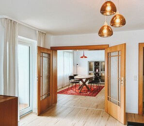 A spacious room with wooden flooring, a dining area with a red rug, and a kitchen in the background. - NEW: Spacious suite with private terrace | 10 min from Rothenburg, ob der Tauber (Schrozberg)