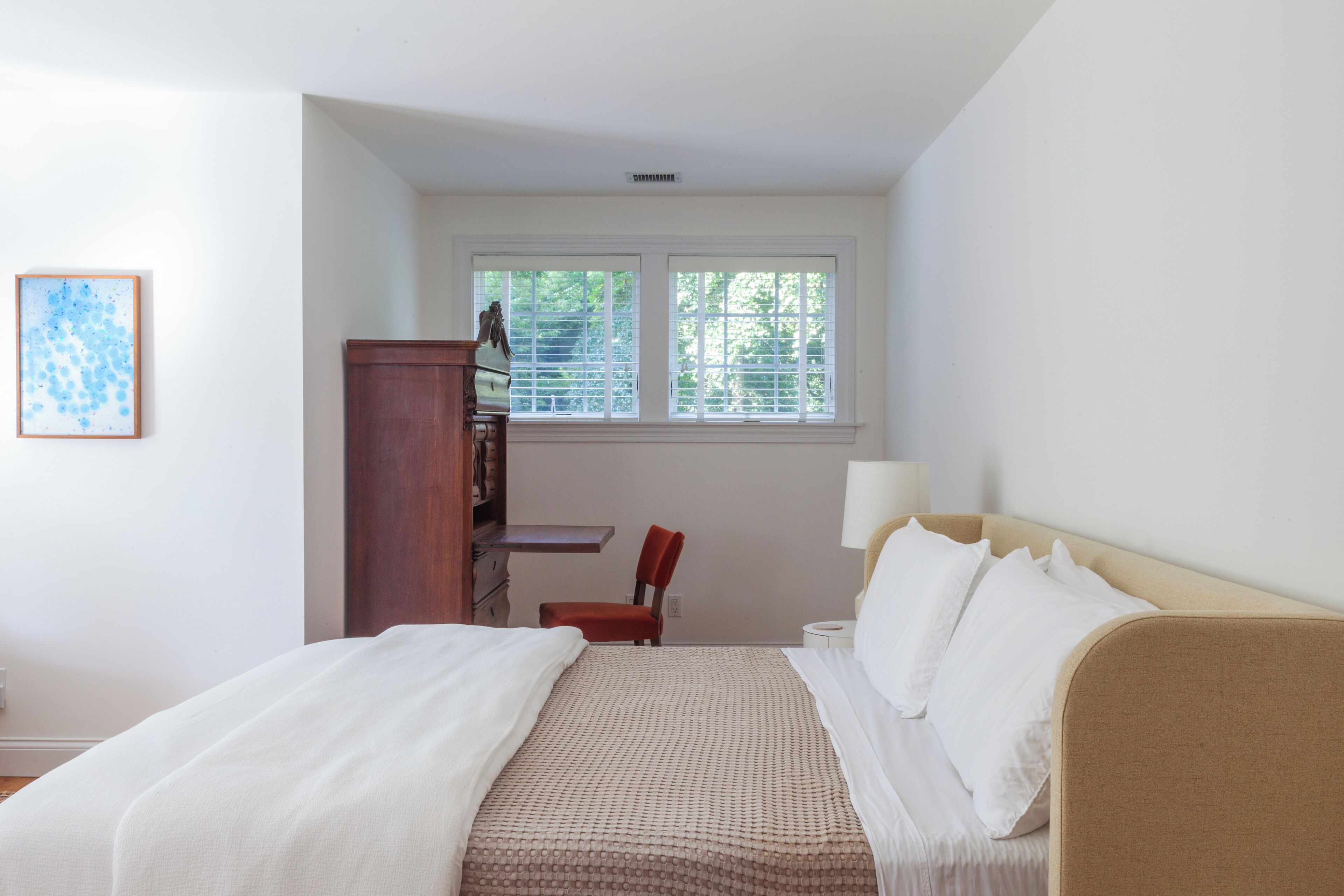 Un dormitorio con cama, escritorio, silla y ventana.
