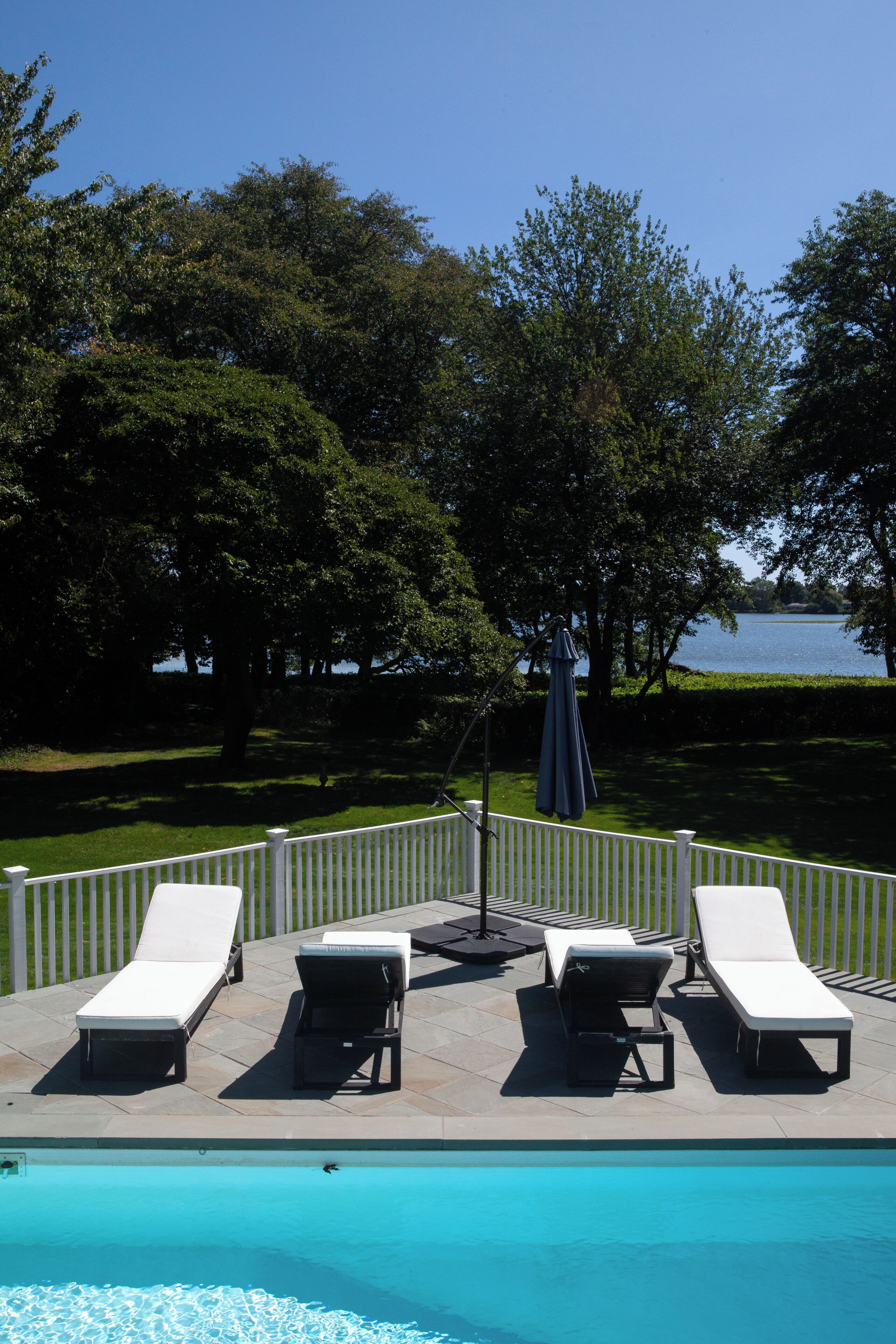 A poolside area with lounge chairs and a view of a lake.