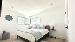 A bedroom with a bed, bedside tables, a fluffy rug, and a decorative wall piece.