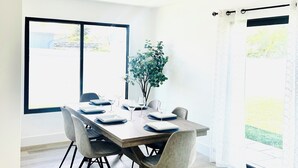 A dining area with a wooden table, grey chairs, and a potted plant.