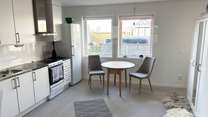 Una cocina moderna con armarios blancos, una estufa y una zona de comedor con dos sillas y una mesa.