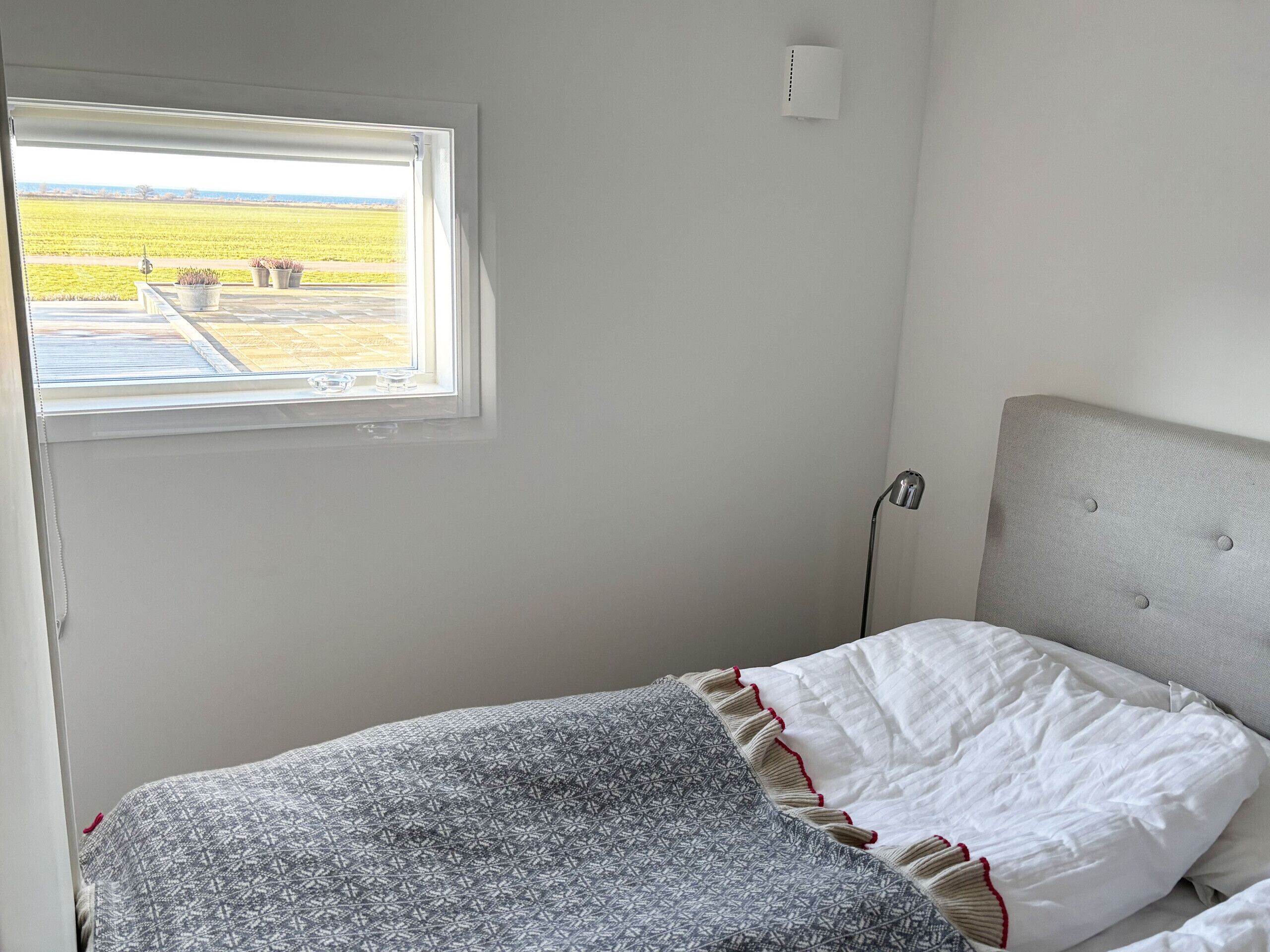A bedroom with a window, a bedside lamp, and a bed with patterned bedding.