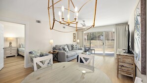 Un salon moderne avec une table ronde en verre, un canapé gris et une table basse en bois.