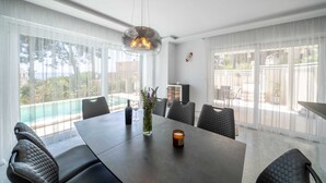 A modern dining area with a large table, cushioned chairs, and a pendant light. - Villa Noemi by MyWaycation (Sumartin)