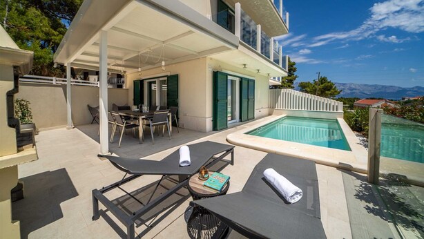 A modern outdoor area with a pool, a covered patio, and a dining setup. - Villa Noemi by MyWaycation (Sumartin)