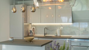 A modern kitchen with a marble backsplash, a central island with a bowl, pendant lights, and stainless steel appliances. - Villa Noemi by MyWaycation (Sumartin)