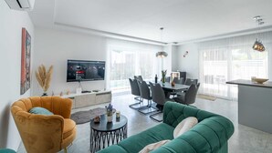 A modern living room with a sofa, a coffee table, and a TV mounted on the wall. - Villa Noemi by MyWaycation (Sumartin)
