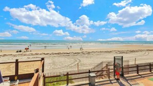 A beach with a wooden fence and a person standing near the gate. - NEW Amazing Ocean Front King Bed Studio in Daytona! (Daytona Beach)