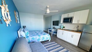 A bedroom with a bed, a sofa, a desk, and a kitchenette. - NEW Amazing Ocean Front King Bed Studio in Daytona! (Daytona Beach)