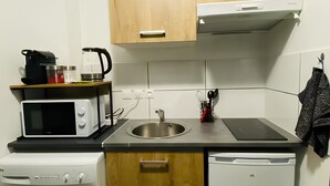 Une cuisine compacte avec des meubles en bois, un four à micro-ondes encastré, un évier, un lave-vaisselle et un lave-linge.