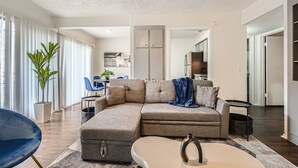 A modern living room with a sectional sofa, a coffee table, and a dining area with a blue chair.