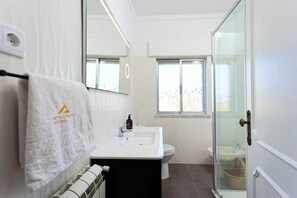 A modern bathroom with a white sink, a toilet, and a glass shower enclosure. - Refúgios do Rio Dão - Comfort and privacy in the heart of the Dão Lafões region. (Viseu)