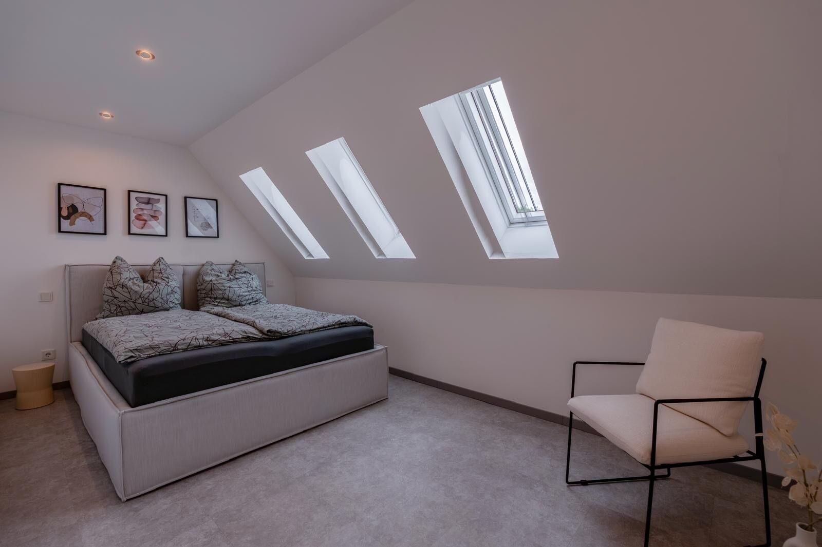 Une chambre à coucher avec un lit, une chaise et des fenêtres de toit.