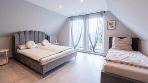 Ein modernes Schlafzimmer mit einem großen Bett, einem kleineren Bett und einer Sitzecke.