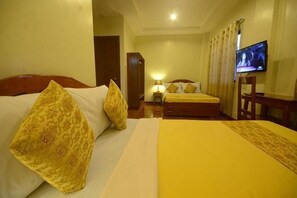Una habitación de hotel con dos camas, televisión y escritorio.