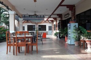 An indoor area with tables and chairs, a ceiling fan, and potted plants. - Angelic Mansion Palawan (Puerto Princesa)