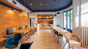 Un'area pranzo moderna con pareti in legno, un tavolo lungo e sedie blu.
