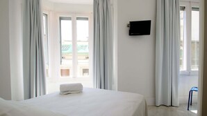 A hotel room with a bed, a TV on the wall, and a view of the outside. - Dingdong Express Hostel (Barcelona)