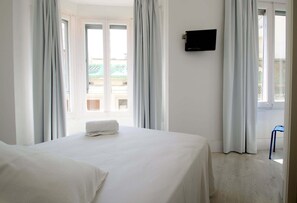A hotel room with a bed, a TV on the wall, and a view of the outside. - Dingdong Express Hostel (Barcelona)