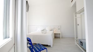 A white room with a bed, a blue chair, and a nightstand. - Dingdong Express Hostel (Barcelona)