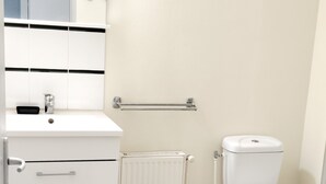 A modern bathroom with a white sink, mirror, toilet, and radiator. - Studio+outside Ribérac town center2 (Ribérac)