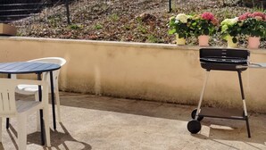 An outdoor patio area with a table and chairs, a barbecue grill, and potted plants. - Studio+outside Ribérac town center2 (Ribérac)