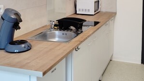 A compact kitchen with white cabinets, a microwave, a coffee machine, and a sink. - Studio+outside Ribérac town center2 (Ribérac)