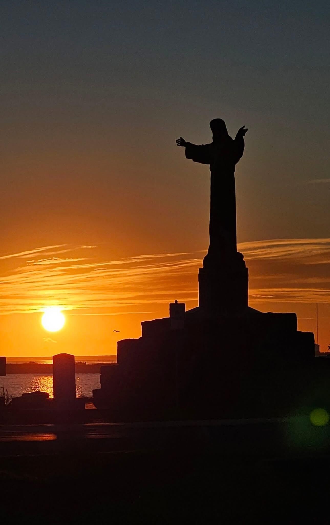 Eine Statue im Silhouettenbild vor einem Sonnenuntergang.