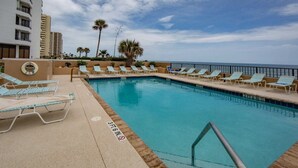 Une piscine avec des chaises longues, un poste de surveillance pour les sauveteurs et une vue sur l’océan.