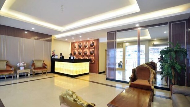 Un vestíbulo de hotel con mostrador de recepción, zona de estar y una planta grande.